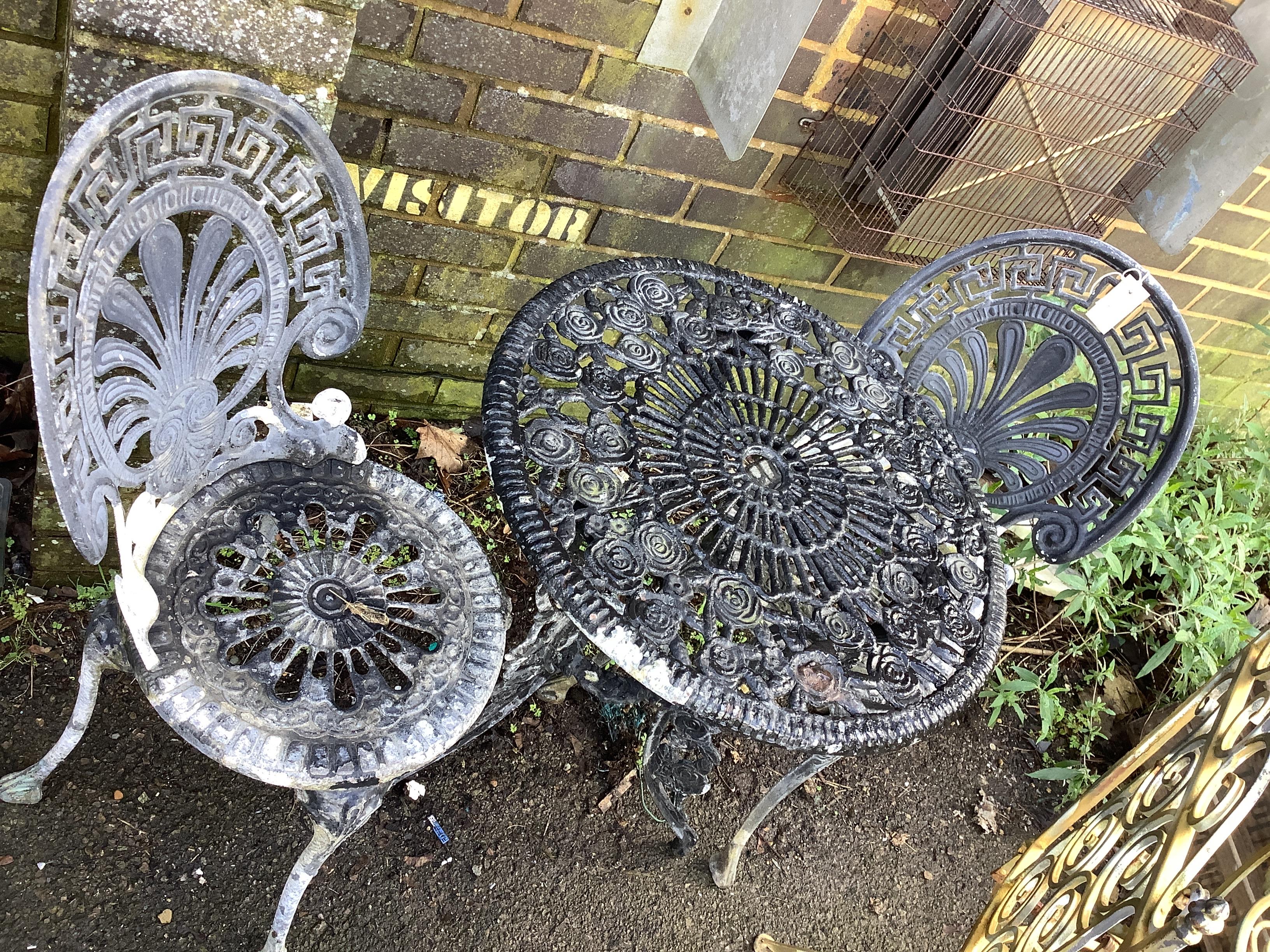 A circular Victorian style metal garden table, diameter 60cm, height 68cm and two chairs